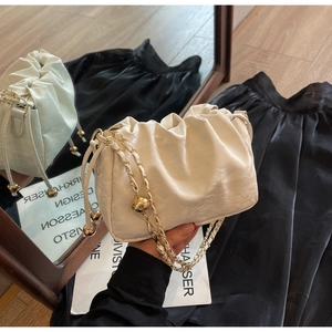Detail view of off-white pleated cloud bag with elegant gold interwoven chain strap