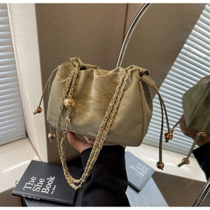 Detail of light green pleated cloud bag with gold chain strap and adjustable metal ball