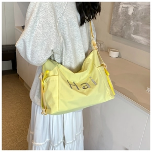 Detail view of bright yellow nylon tote bag with Hai lettering and adjustable shoulder strap