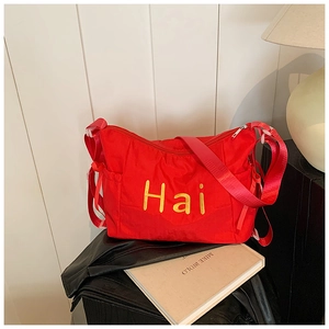 Detail of red nylon shoulder bag with yellow Hai print and adjustable wide strap