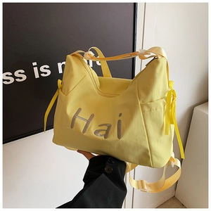 Detail of yellow nylon shoulder bag featuring grey Hai print and ribbon side accents