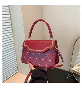 Detail of red quilted handbag with golden heart embroidery and textured PU leather