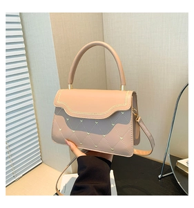 Detail of light pink quilted handbag featuring gold heart accents and elegant hardware