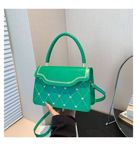 Detail of green quilted crossbody bag featuring heart embroidery and wavy edge design