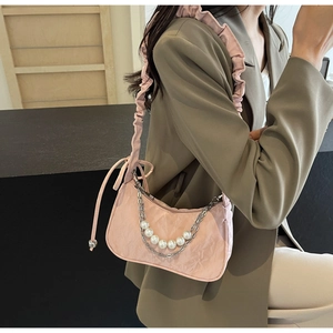 Détail latéral du sac plissé rose avec décoration de perles et chaîne en métal