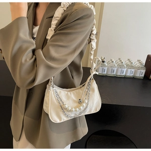 Détail du sac d'épaule plissé blanc avec chaîne en perles et tissu à texture gaufrée
