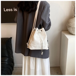 Detail of white water-ripple drawstring bucket bag with elegant pearl charm and leather strap