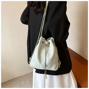 Detail of mint green bucket bag featuring a silver butterfly charm and pearl pendant