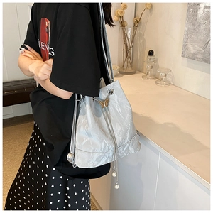 Detail of silver drawstring bucket bag with gold butterfly and large pearl charms