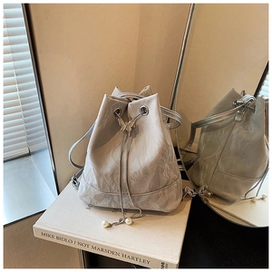 Detail of silver pleated bucket bag featuring butterfly metal clasp and pearl drawstring