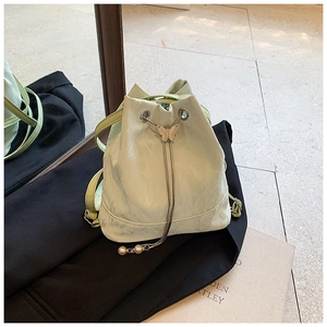 Detail of light green bucket bag with wavy texture, pearl charms and butterfly slider