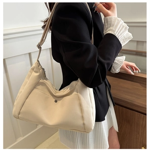 Détail montrant la bandoulière réglable et la poche à bouton du sac en nylon beige