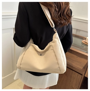 Sac hobo en nylon beige avec bandoulière réglable et détail de la poche frontale