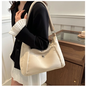 Detailed view of beige nylon crossbody bag featuring wide shoulder strap and metal snap button