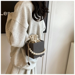 Detail of grey tweed crossbody bag with large pearl handle and gold metal chain strap