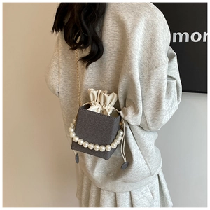 Detail of grey tweed bucket bag with elegant pearl handle and gold chain strap