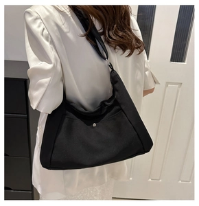 Gros plan sur le sac demi-lune en toile noire avec bandoulière et poche à bouton