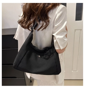 Rear view of model wearing black canvas tote bag with silver magnetic closure button