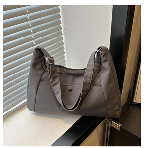 Close-up of dark grey tote bag with wide strap and metal snap button pocket detail