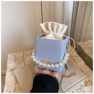 Detail of blue denim bucket bag with large pearl handle and golden chain strap