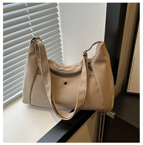 Detail of beige canvas tote bag with front buckle pocket and durable twin handles
