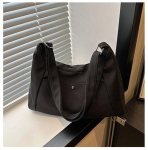 Detail showing the durable black nylon fabric and functional metal snap pocket of the bag
