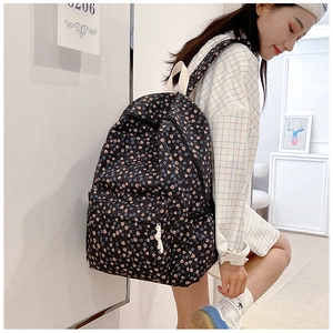 Detailed shot of black floral backpack with tulip patterns and white shoulder straps