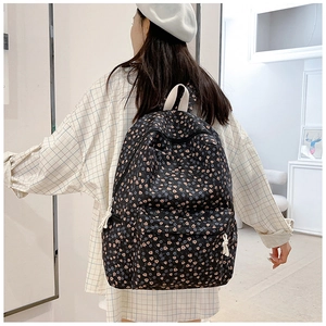Detail of floral black backpack with pink flower patterns worn by a model in casual style