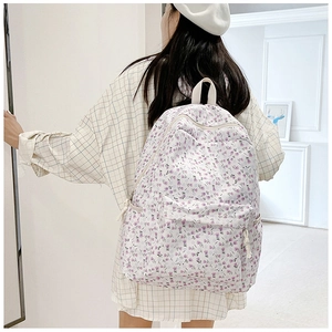 Back view of a model wearing a canvas floral backpack with purple tulip patterns