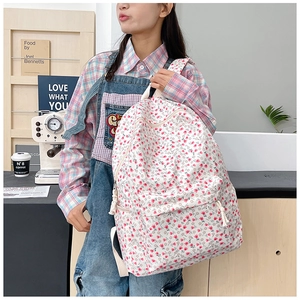 Close-up of white floral backpack with pink tulips and front zipper pocket detail