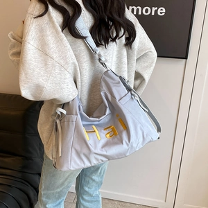 Minimalist light blue-grey large canvas hobo bag with yellow text on shoulder