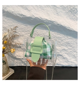 Detail van transparante PVC-handtas met groene leren flap en zilveren ketting