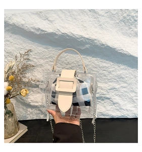 Detail van transparante PVC jelly tas met blauwe ruitjesvoering en metalen ketting