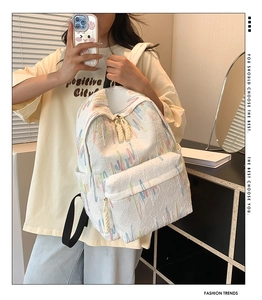 Dettaglio di uno zaino bianco con ricami colorati e tirazip in corda intrecciata