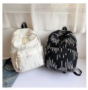 Dettaglio del ricamo a onde su zaini casual eleganti nei colori beige e nero