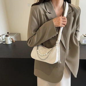 Sac crème avec chaîne de perles et bandoulière froncée sur un blazer kaki