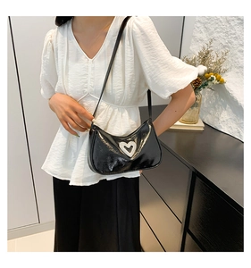Detail of black patent leather shoulder bag with a large sparkling rhinestone heart charm