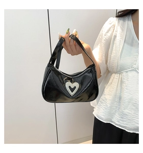 Macro shot of silver rhinestone heart ornament on glossy black patent leather bag
