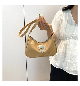 Detail of beige rhinestone heart buckle on chic synthetic leather underarm bag