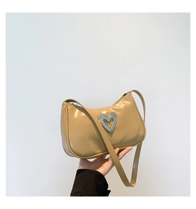 Detail of beige shoulder bag featuring a large sparkling rhinestone heart decoration
