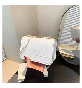 Gros plan du sac matelassé blanc avec chaîne dorée et détails de texte tendance