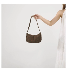 Détail du sac sous le bras en velours côtelé marron café avec motif de cœur rouge et bandoulière