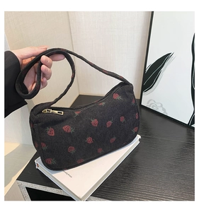 Détail du sac croissant en velours côtelé noir avec broderie fraise et fermeture dorée