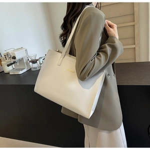 Detailed side view of a cream leather tote bag with elegant gold script lettering