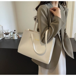 Close-up of cream tote bag with fine synthetic leather texture and gold metal logo