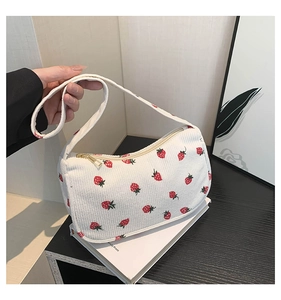 Détail du sac bandoulière en velours côtelé blanc à motifs fraises et zip doré brillant