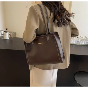Detail of chocolate brown tote bag with white contrast stitching and gold logo
