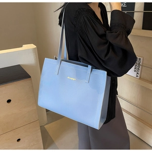 Detailed view of light blue tote bag with fine leather texture and slim shoulder straps