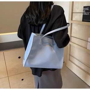 Detail of light blue leather tote bag with white contrast stitching and gold logo
