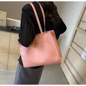 Detail of light pink leather tote bag featuring golden logo and spacious trapezoid design
